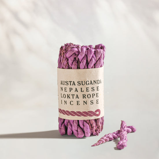 Austa Suganda Lokta Rope Incense Bundle: lilac twisted rope incense in a kraft paper band, two loose ropes beside it.