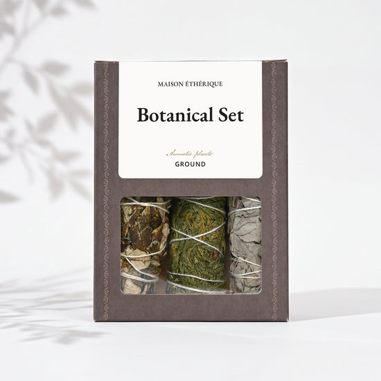 Botanical Set — Ground: grey-brown Maison Éthérique box with a window showing three bundles of white sage, cedar and yerba santa.