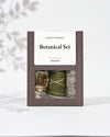 Botanical Set — Ground: grey-brown Maison Éthérique box with a window showing three bundles of white sage, cedar and yerba santa.
