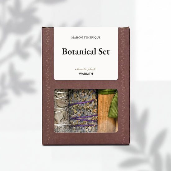 Botanical Set — Warmth: brown Maison Éthérique box with a window showing white sage, lavender and Palo Santo tied with green ribbon.