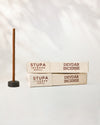 Devdar incense sticks, tube of 15: two Stupa paper boxes beside a stick standing in a small holder.