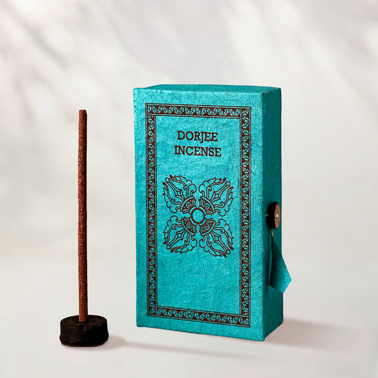 Dorjee Incense Sticks, box of 40: turquoise Stupa paper box with dark print beside a stick standing in a small holder.