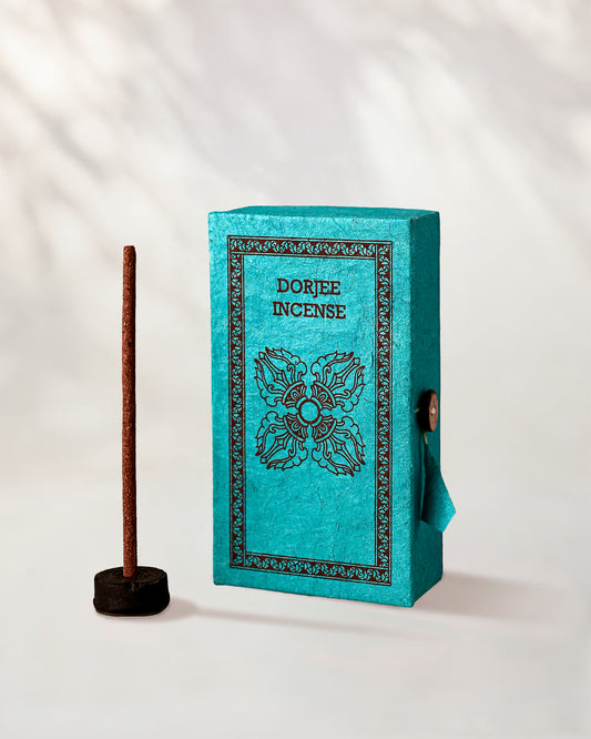 Dorjee Incense Sticks, box of 40: turquoise Stupa paper box with dark print beside a stick standing in a small holder.