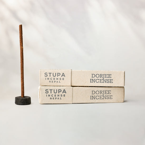 Dorjee Stupa incense, tube of 15 sticks: two paper boxes beside a stick standing in a small holder.