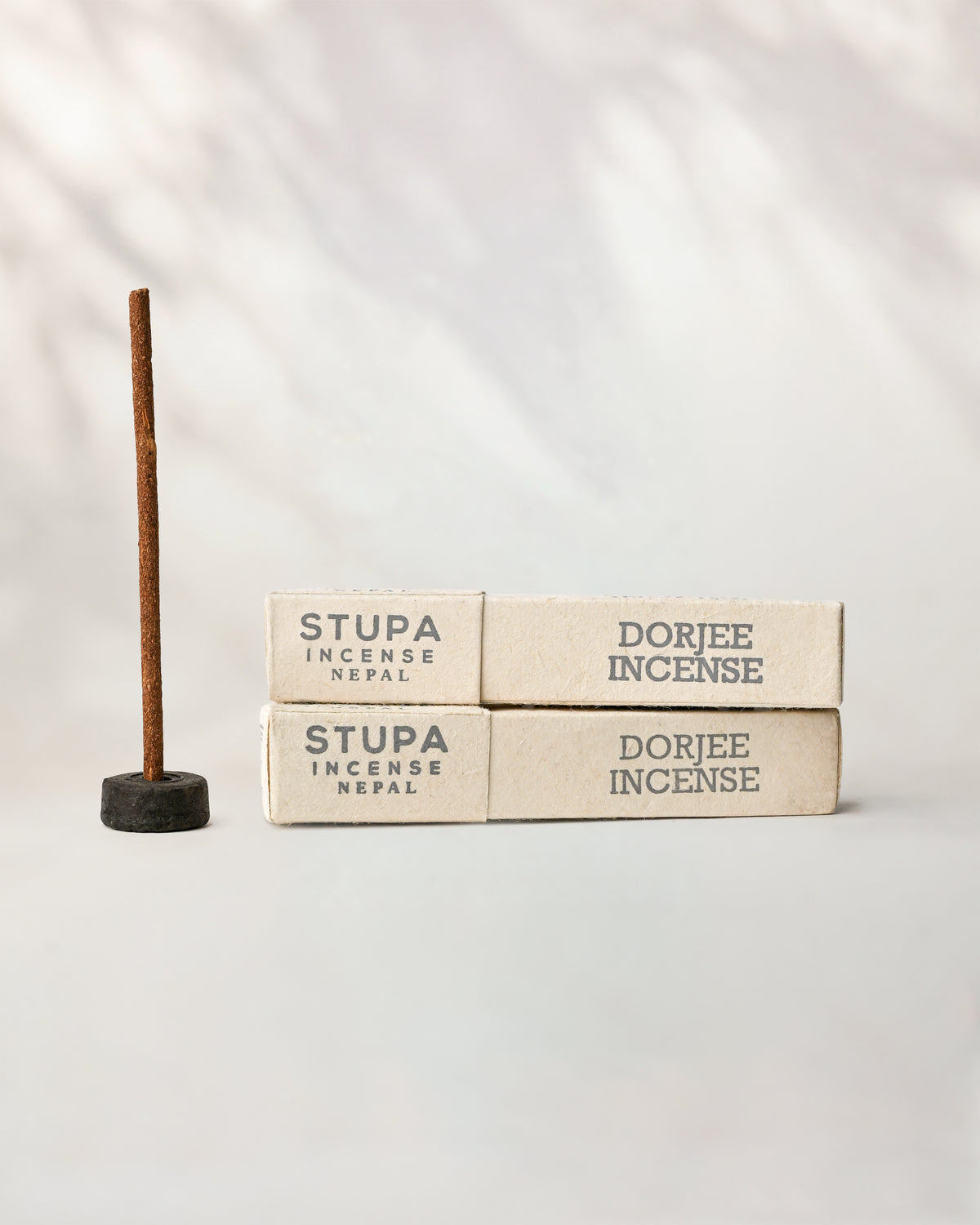 Dorjee Stupa incense, tube of 15 sticks: two paper boxes beside a stick standing in a small holder.