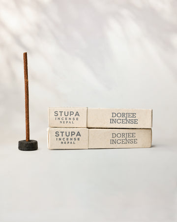 Dorjee Stupa incense, tube of 15 sticks: two paper boxes beside a stick standing in a small holder.