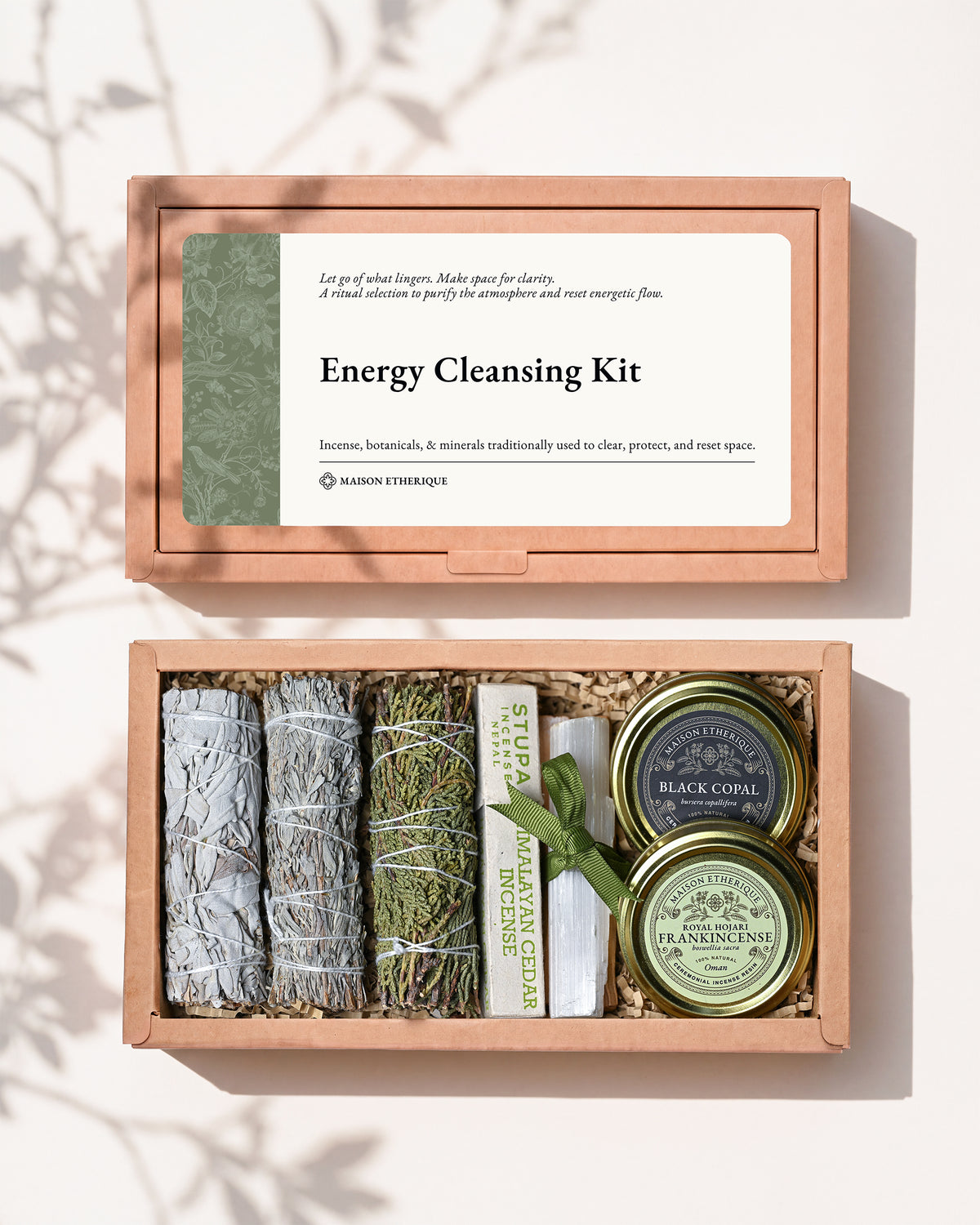 Energy Cleansing Kit: kraft box lid above the open box with three smudge sticks, Palo Santo, Himalayan Cedar incense and tins of frankincense and black copal.