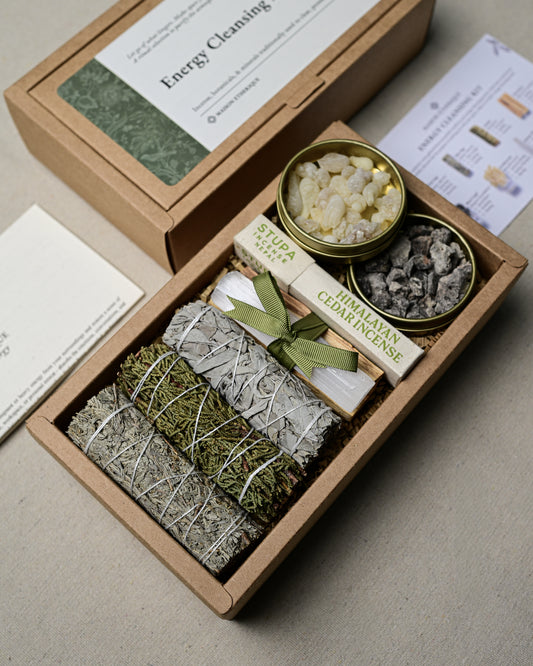 Open kraft kit box seen at an angle with three smudge sticks, ribbon-tied Palo Santo, a box of Himalayan Cedar incense and two open resin tins.