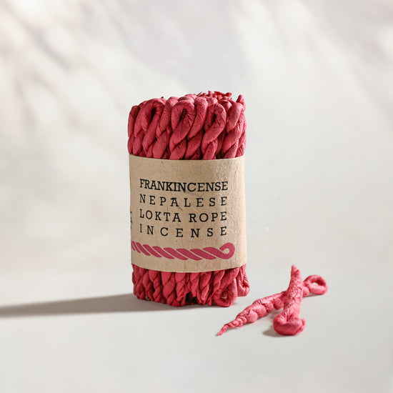 Frankincense Lokta Rope Incense Bundle: red twisted rope incense in a kraft paper band, two loose ropes beside it.