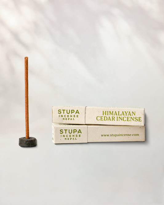 Himalayan Cedar incense, tube of 15 sticks: two Stupa paper boxes beside a stick standing in a small holder.