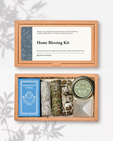 Home Blessing Kit: kraft box lid above the open box with sandalwood incense, three smudge sticks, a frankincense tin and a white crystal pyramid.
