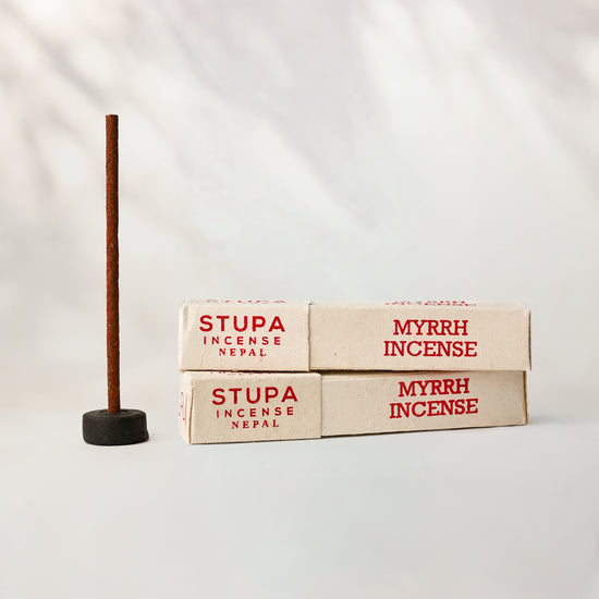 Myrrh incense, tube of 15 sticks: two Stupa paper boxes beside a stick standing in a small holder.