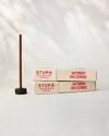 Myrrh incense, tube of 15 sticks: two Stupa paper boxes beside a stick standing in a small holder.