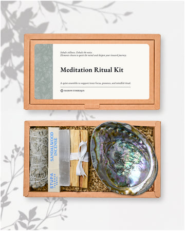 Meditation Ritual Kit: kraft box lid above the open box with a white sage stick, sandalwood incense, Palo Santo and an abalone shell.