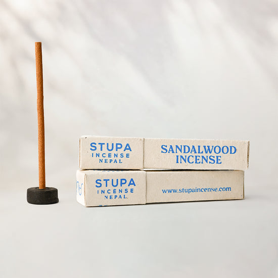 Sandalwood Stupa incense sticks, tube of 15: two paper boxes beside a stick standing in a small holder.