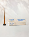 Sandalwood Stupa incense sticks, tube of 15: two paper boxes beside a stick standing in a small holder.