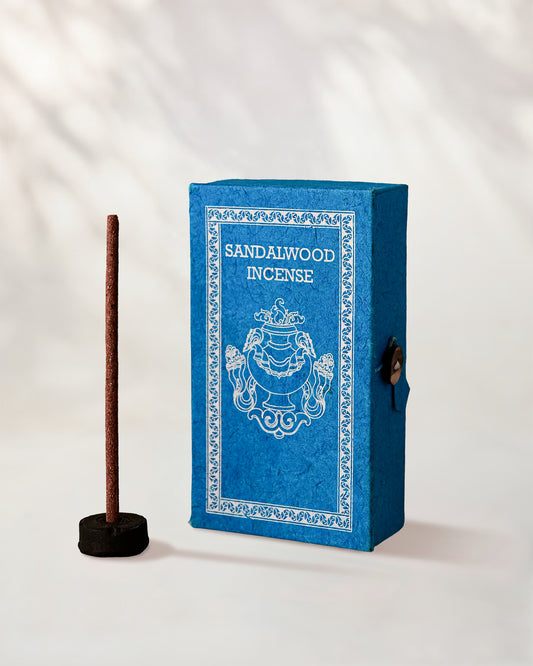 Sandalwood Stupa Incense Sticks, box of 40: blue paper box with white print beside a stick standing in a small holder.