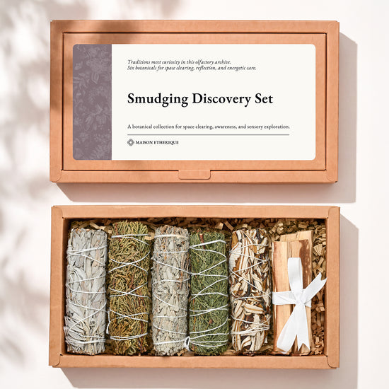 Smudging Discovery Set: kraft box lid above the open box with five smudge sticks and a ribbon-tied Palo Santo bundle.