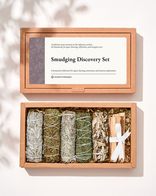 Smudging Discovery Set: kraft box lid above the open box with five smudge sticks and a ribbon-tied Palo Santo bundle.