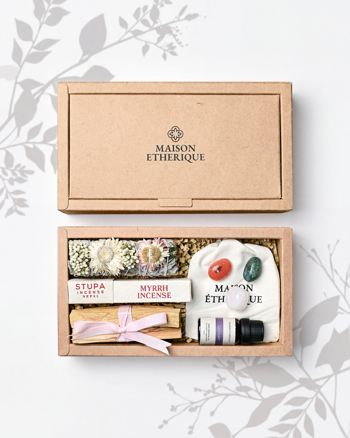Whispers of Joy: open kraft Maison Éthérique box holding a herb bundle, myrrh incense, Palo Santo, lavender oil and tumbled stones.