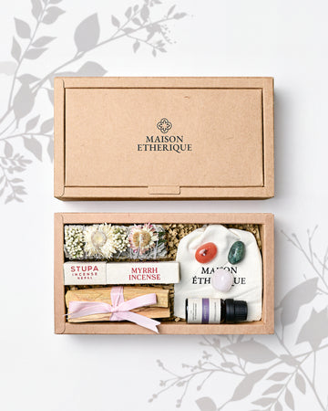 Whispers of Joy: open kraft Maison Éthérique box holding a herb bundle, myrrh incense, Palo Santo, lavender oil and tumbled stones.