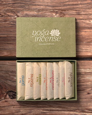 Yoga Incense Gift Box: green handmade paper box with its lid off, eight numbered paper packets of incense inside, on dark wood.