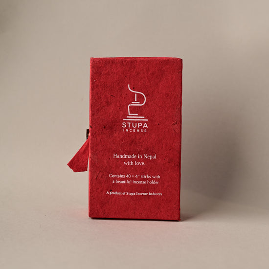 Back of a red paper box of Stupa Austha Suganda incense sticks, handmade in Nepal, on a pale background.