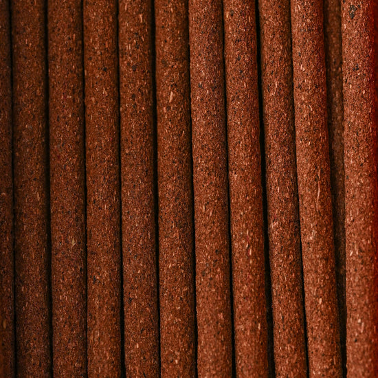 Close view of Austha Suganda incense sticks laid side by side, showing their red-brown texture.