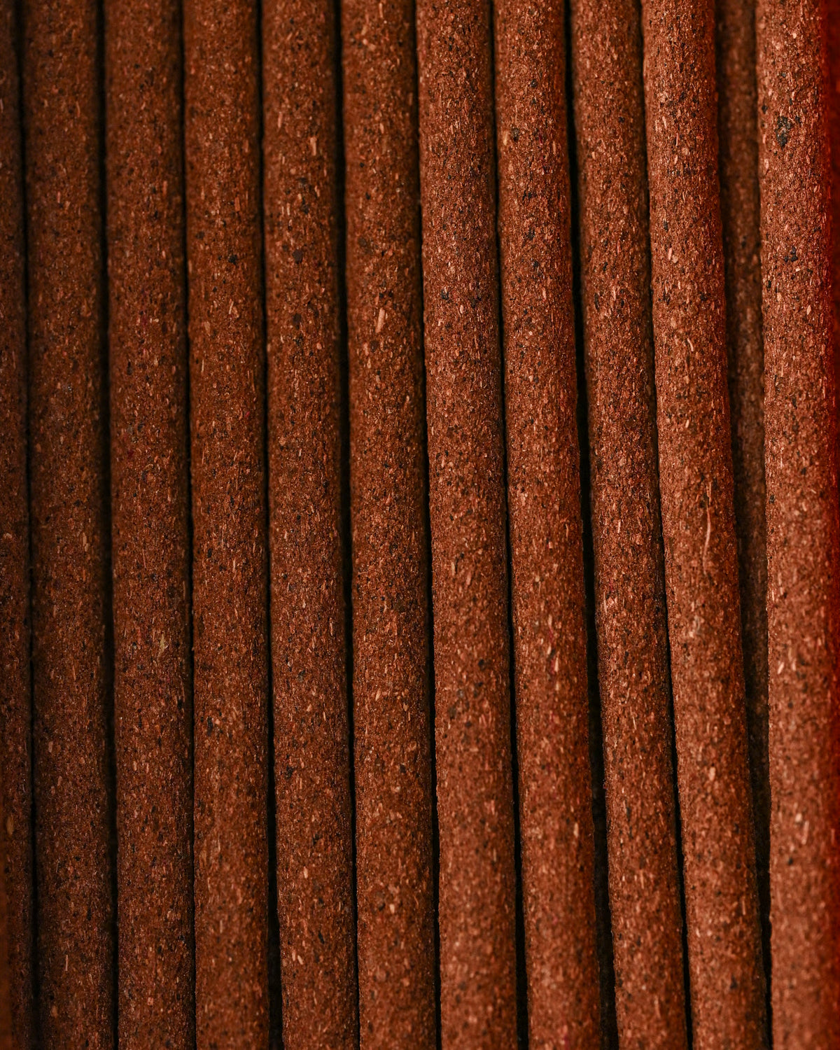Close view of Austha Suganda incense sticks laid side by side, showing their red-brown texture.
