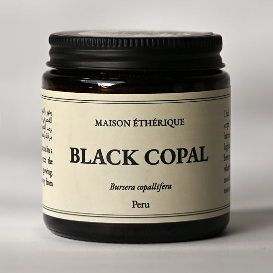 Amber glass jar of Maison Éthérique Black Copal from Peru, black lid, on a pale background.