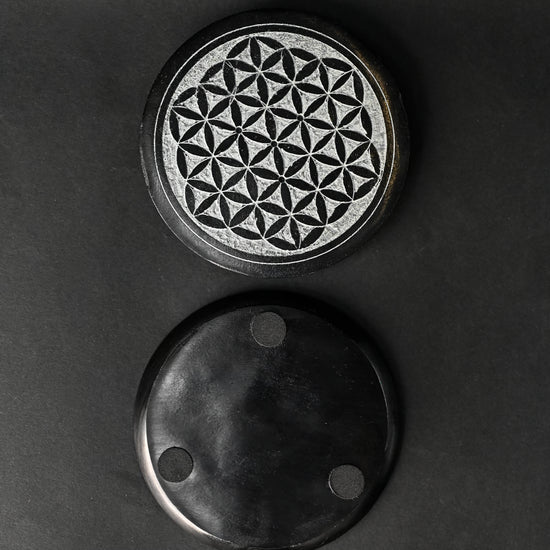 Front and underside of the round Flower of Life stone incense holder, one above the other on a dark background.