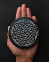 Round Flower of Life stone incense holder resting on an open palm.