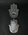 Front and back of the hand-shaped metal incense holder, one above the other on a dark background.