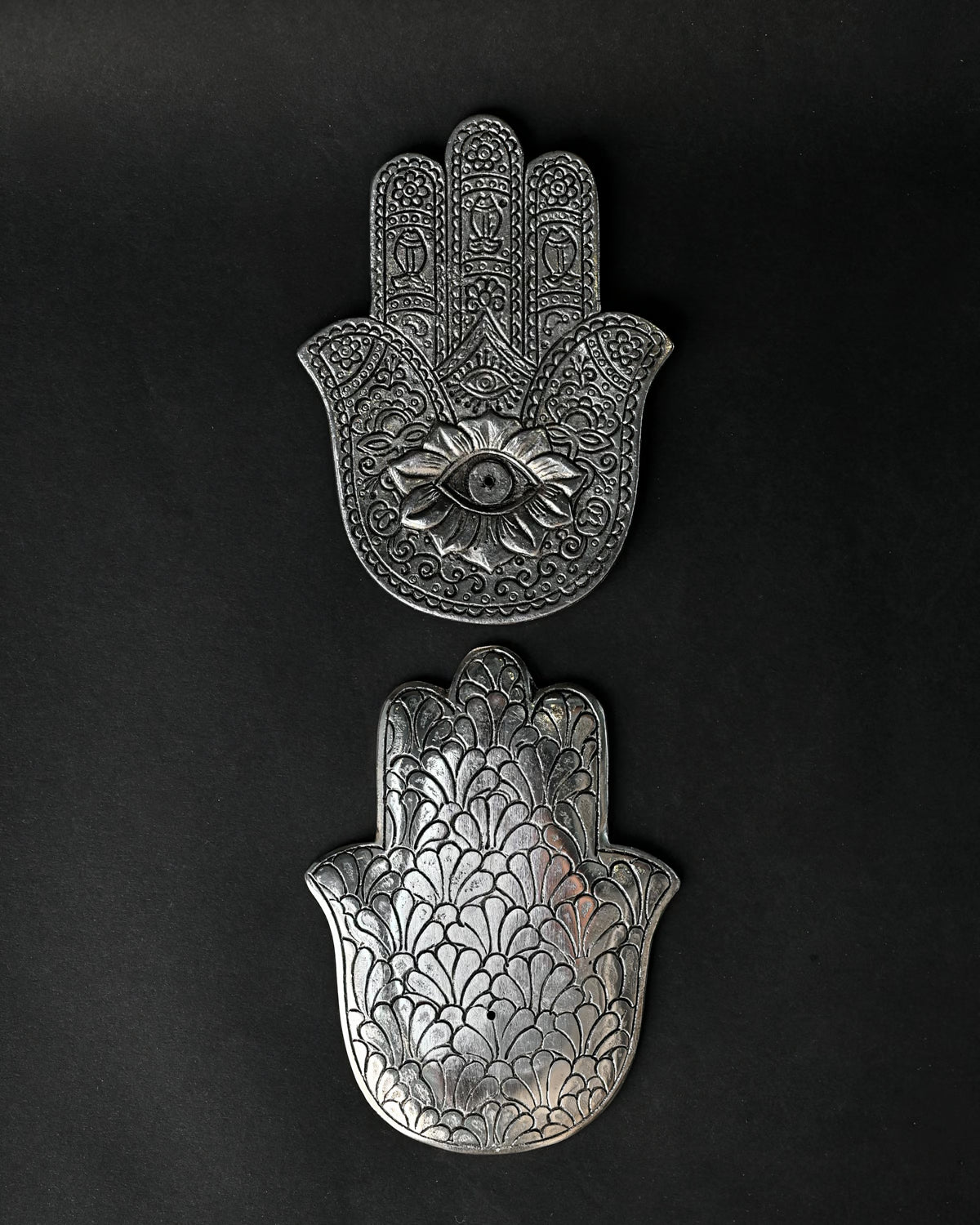 Front and back of the hand-shaped metal incense holder, one above the other on a dark background.