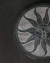 Close view of the sun face carved into the Soleil Noir stone incense holder.