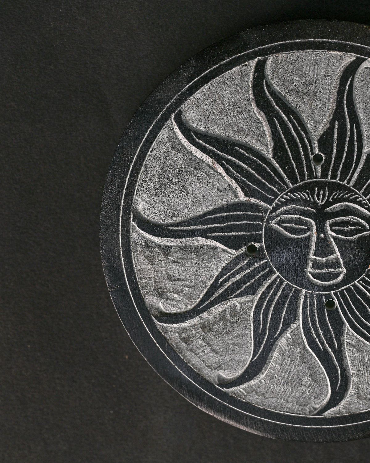 Close view of the sun face carved into the Soleil Noir stone incense holder.