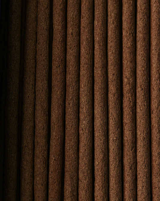 Close view of Nag Champa incense sticks laid side by side, showing their dark brown texture.