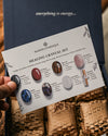 Hand holding the printed guide card of the Maison Éthérique palm stones crystal set above its paper-lined box.