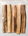 Five hand-cut Palo Santo sticks (Bursera graveolens) from Peru laid side by side on a pale background.