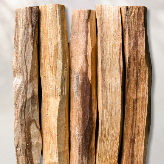 Five hand-cut Palo Santo sticks (Bursera graveolens) from Peru laid side by side on a pale background.