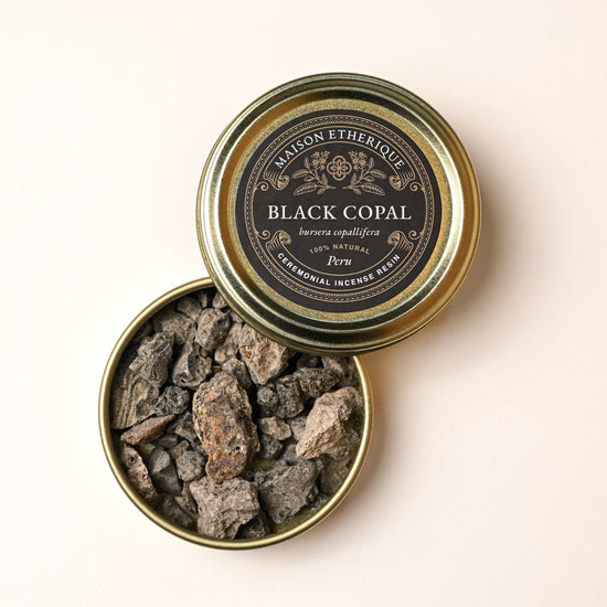 Open gold tin of Maison Éthérique Black Copal (Bursera copallifera) from Peru, grey resin pieces visible inside.
