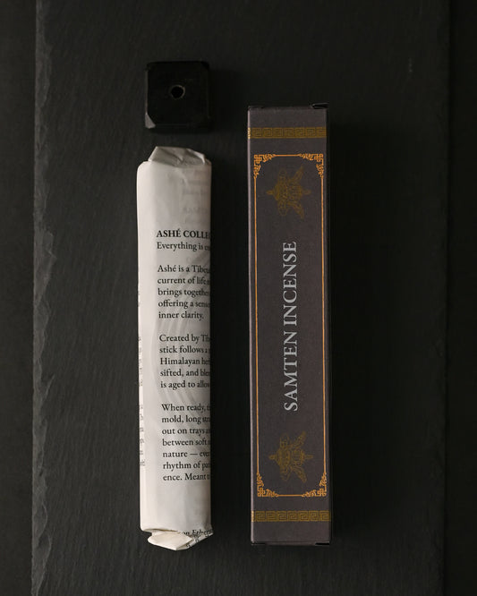 Samten Tibetan incense: paper-wrapped bundle, dark box and small holder laid out on dark slate.