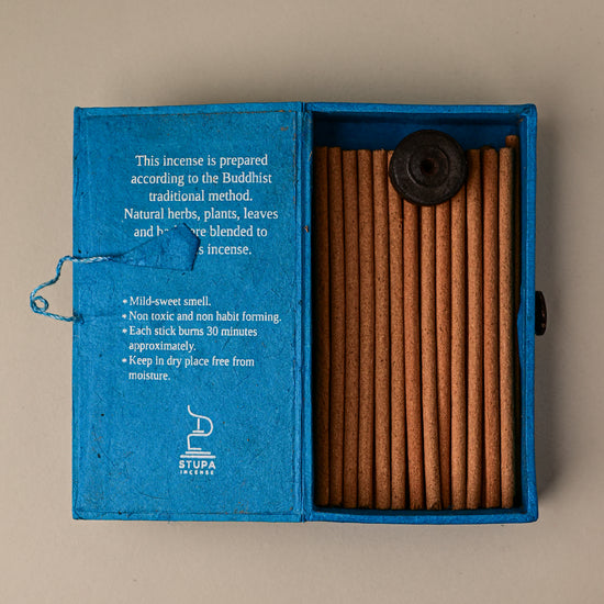 Open blue paper box of Stupa Sandalwood incense sticks from Nepal, the sticks and a small holder visible inside.