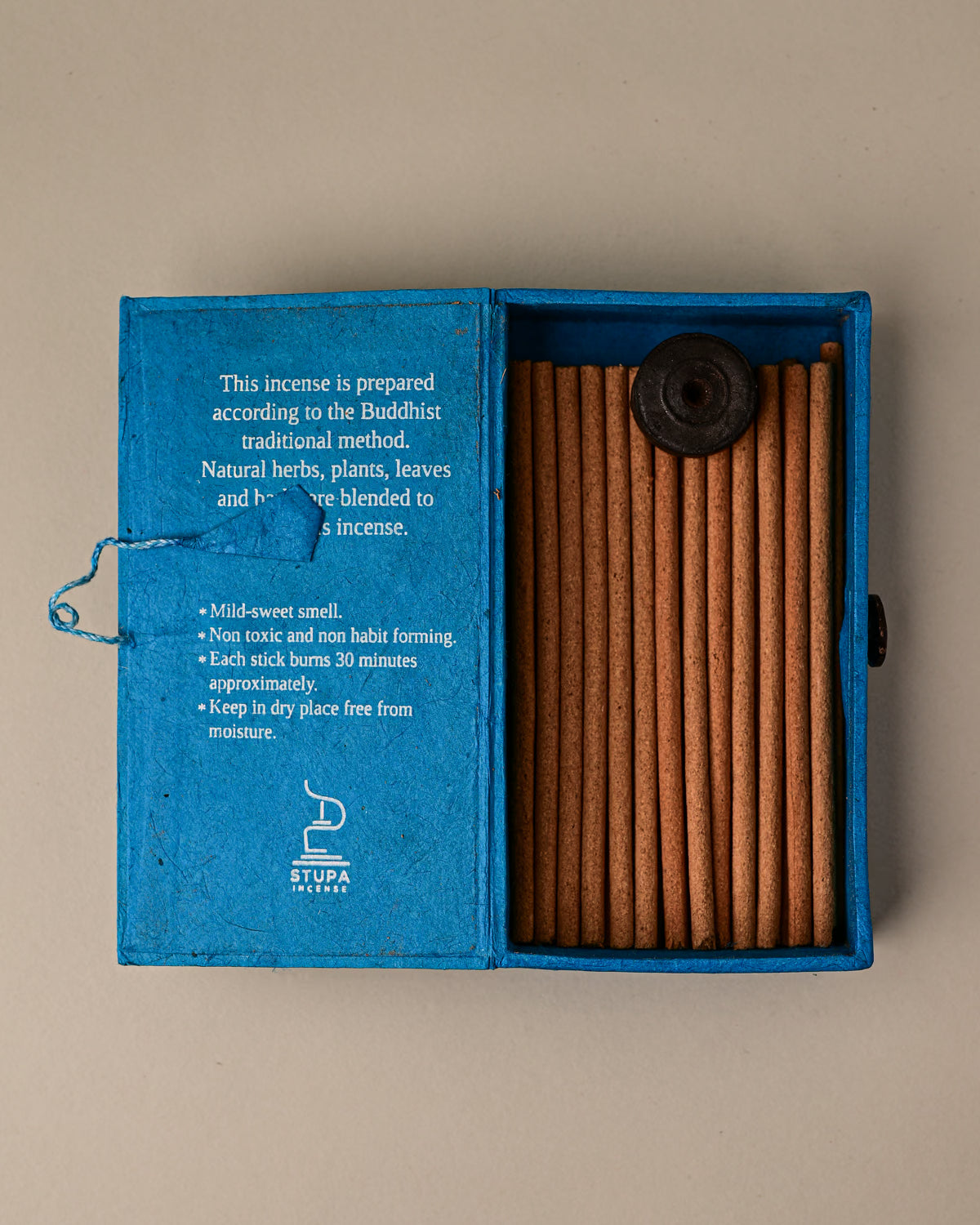 Open blue paper box of Stupa Sandalwood incense sticks from Nepal, the sticks and a small holder visible inside.