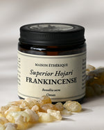 Amber glass jar of Maison Éthérique Superior Hojari Frankincense from Oman with pale frankincense tears in the foreground.