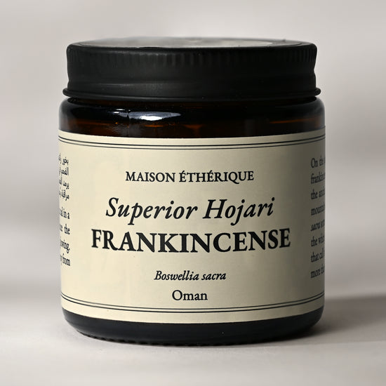 Amber glass jar of Maison Éthérique Superior Hojari Frankincense (Boswellia sacra) from Oman, black lid, on a pale background.