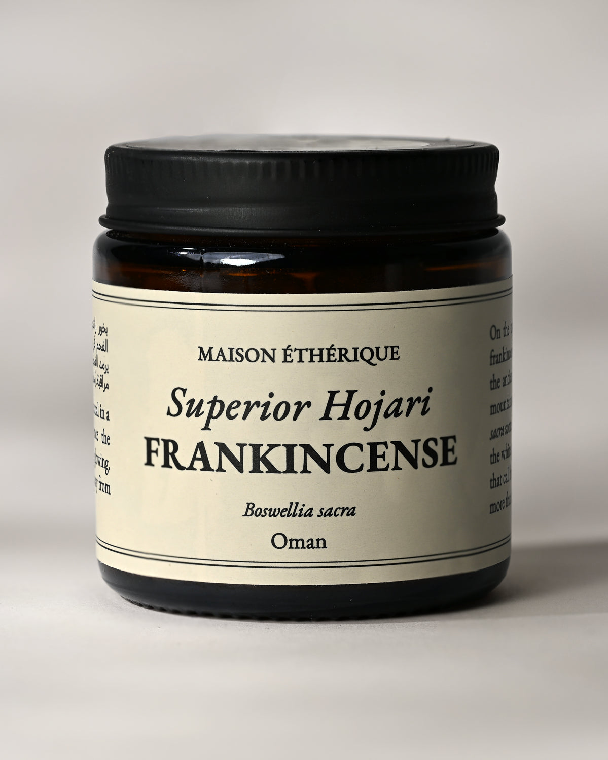 Amber glass jar of Maison Éthérique Superior Hojari Frankincense (Boswellia sacra) from Oman, black lid, on a pale background.
