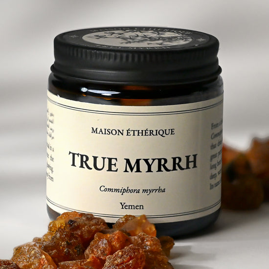 Amber glass jar of Maison Éthérique True Myrrh from Yemen with amber-red myrrh resin pieces in the foreground.