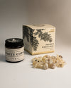 Amber jar and illustrated box of Maison Éthérique Premium White Copal beside a small heap of pale resin pieces.
