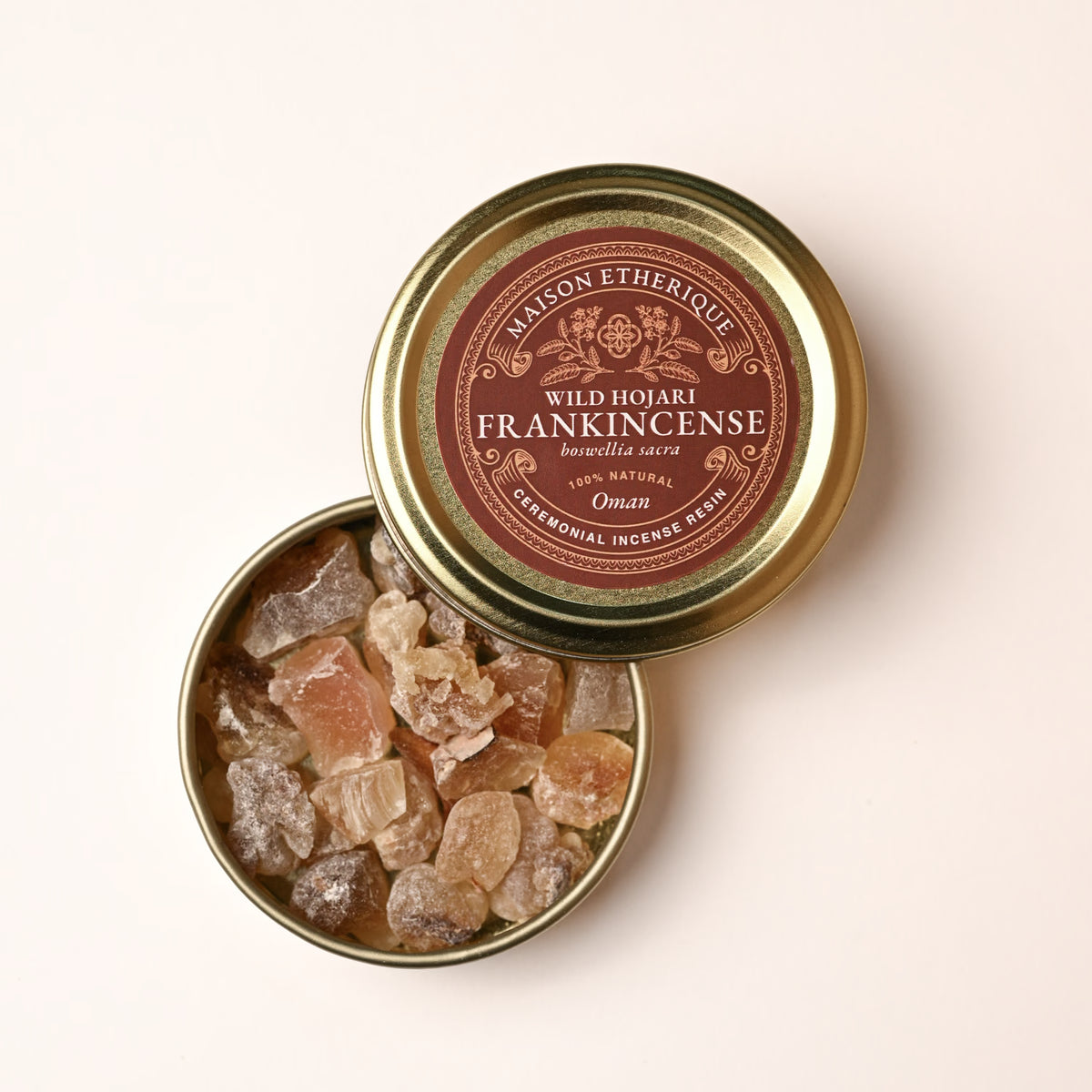 Open gold tin of Maison Éthérique Wild Hojari frankincense (Boswellia sacra) from Oman, pale resin tears visible inside.